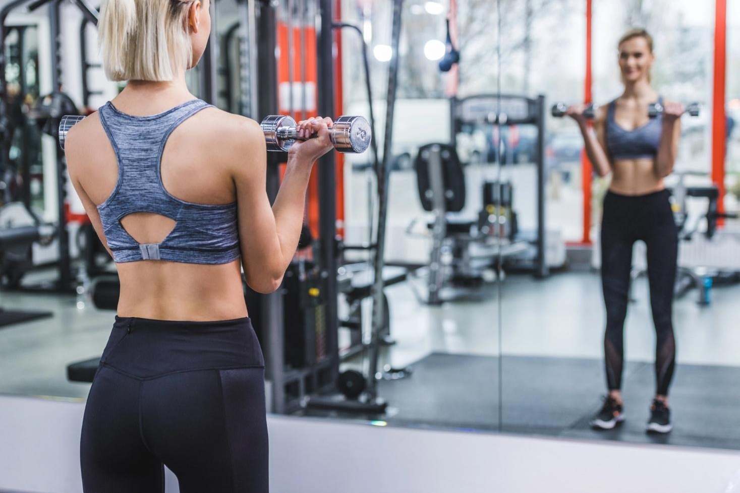 Athletic young woman working out in a modern gym with mirrors.